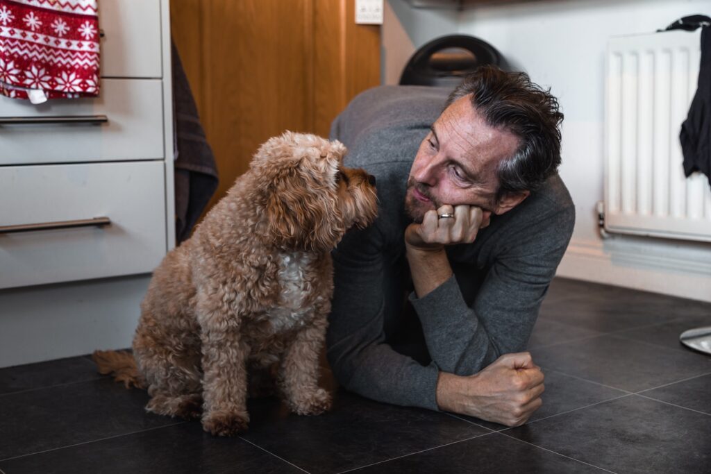 man in black sweater holding brown long coated small dog